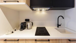 A compact kitchen with a black induction cooktop, a coffee maker, and a kettle. - Kentro Luxury Suites (Kassandra)