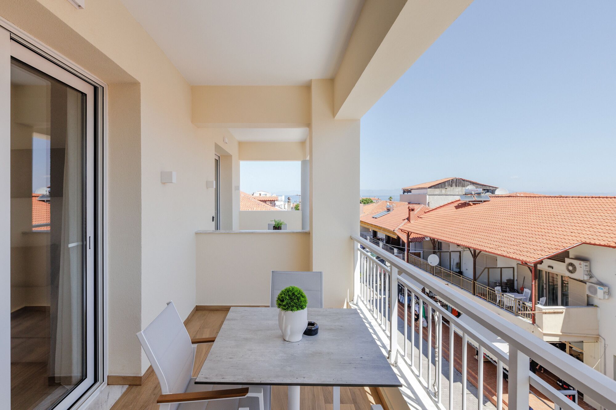 En balkon med et bord, stole og en potteplante.