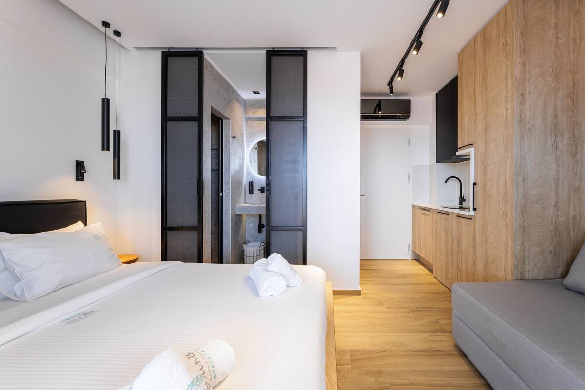Ein modernes Hotelzimmer mit einem großen Bett, einer Couch, einer Küchenzeile und einem Badezimmer.