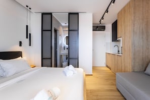 A modern hotel room with a large bed, a sofa, a kitchen area, and a bathroom. - Kentro Luxury Suites (Kassandra)