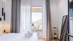 A modern hotel room with a large bed, a balcony with a view, and a small potted plant. - Kentro Luxury Suites (Kassandra)