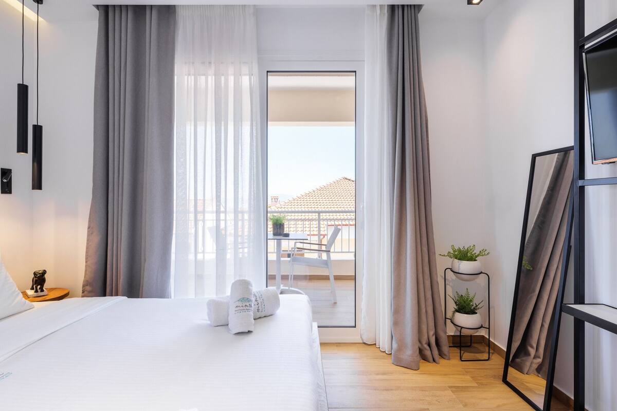 Ein modernes Hotelzimmer mit einem großen Bett, einem Balkon mit Blick und einem kleinen Topfpflanzen.