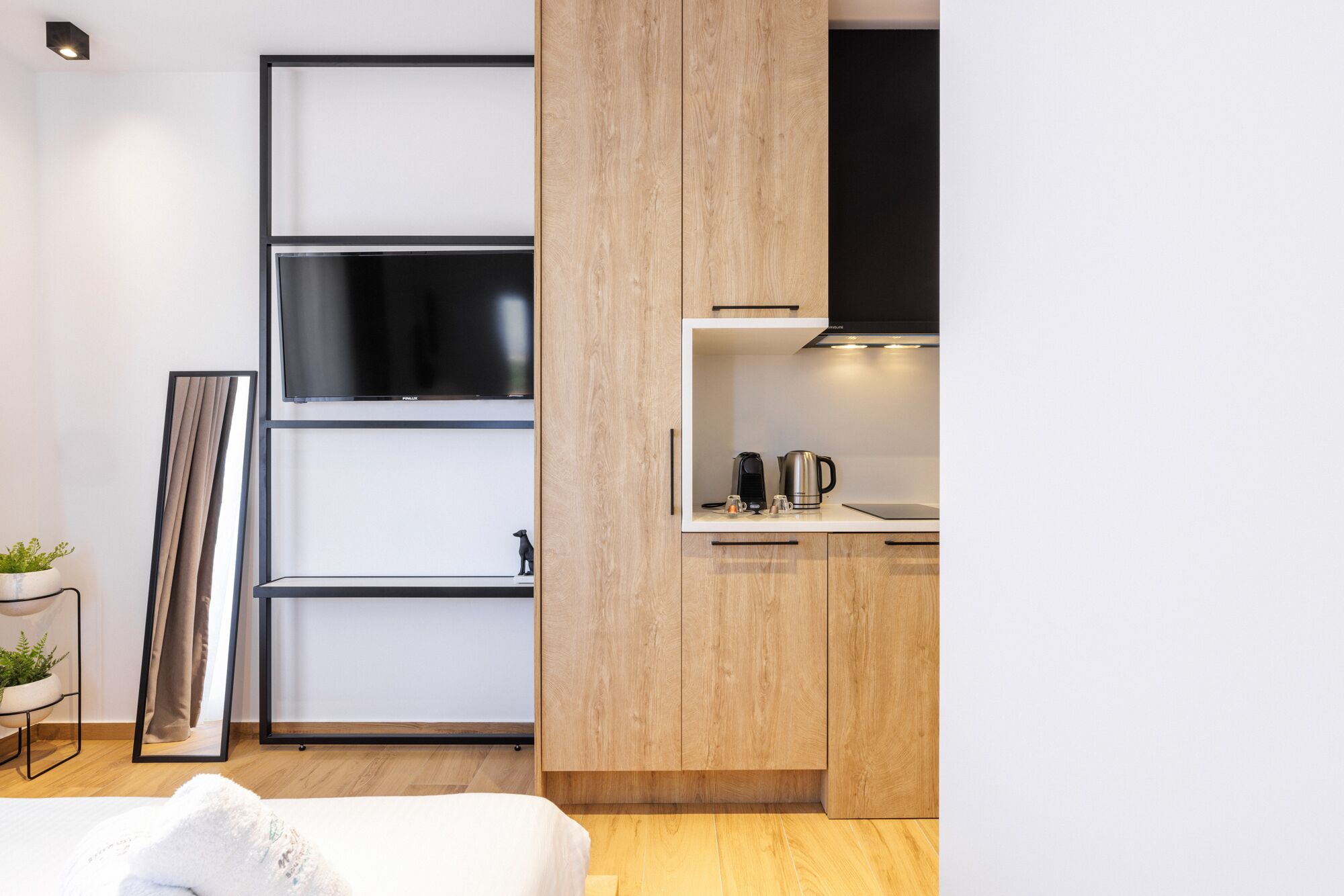 Une cuisine moderne avec des meubles en bois, une hotte noire et une machine à café posée sur le plan de travail.