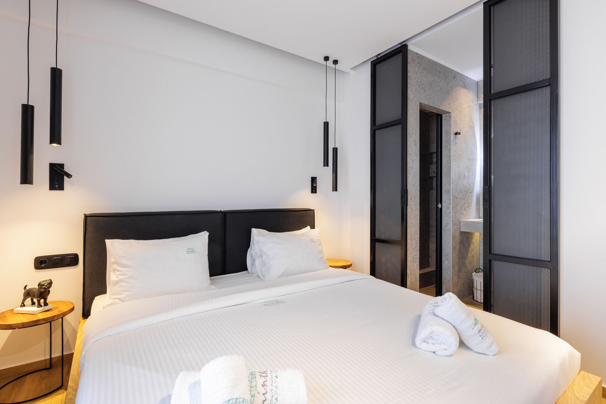 A modern hotel room with a large bed, two bedside tables, and a decorative lion figurine.