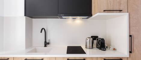 Una cocina moderna con un grifo negro, una placa de inducción integrada y una cafetera.