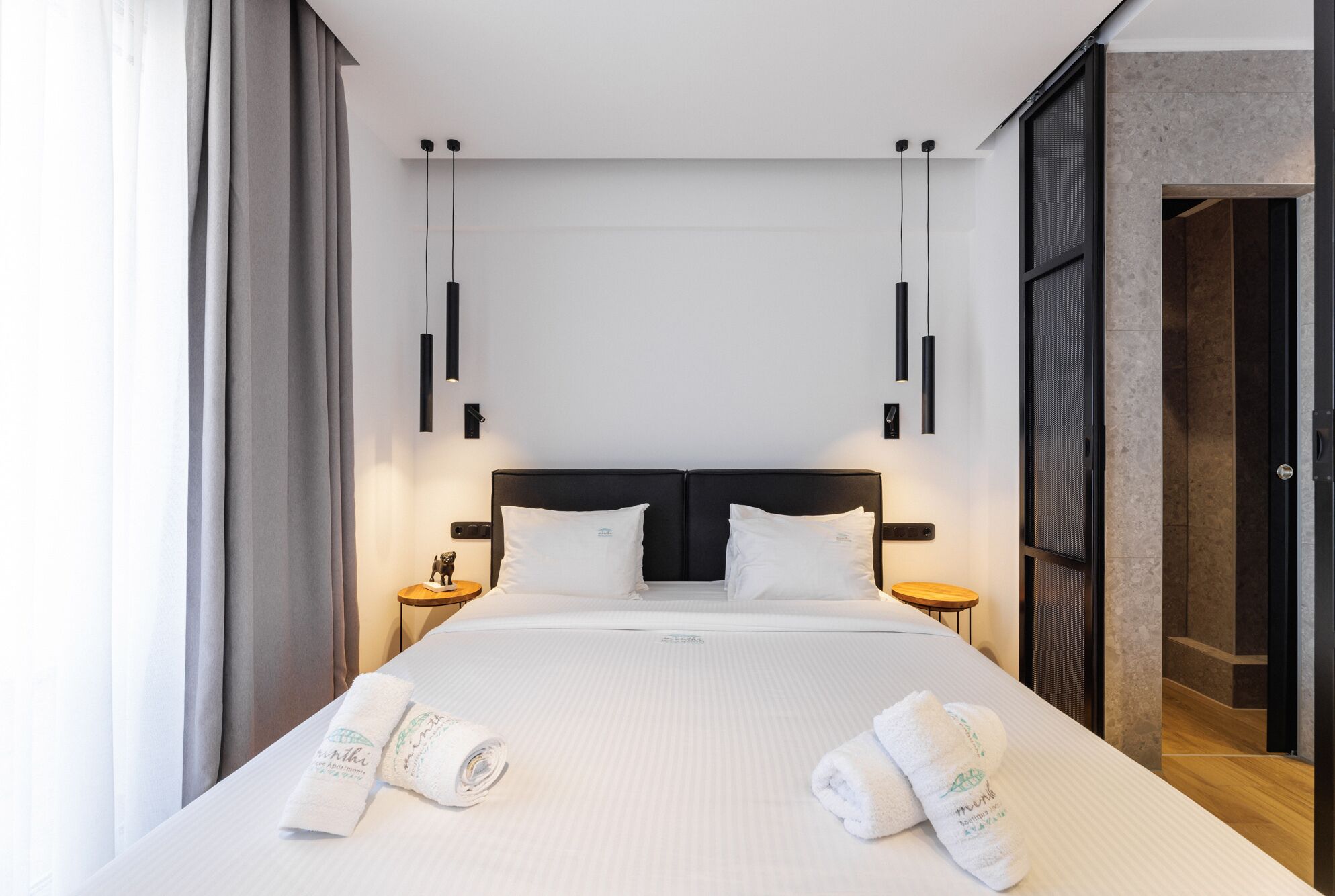 A modern hotel room with a large bed, two bedside tables, and a view of the city.