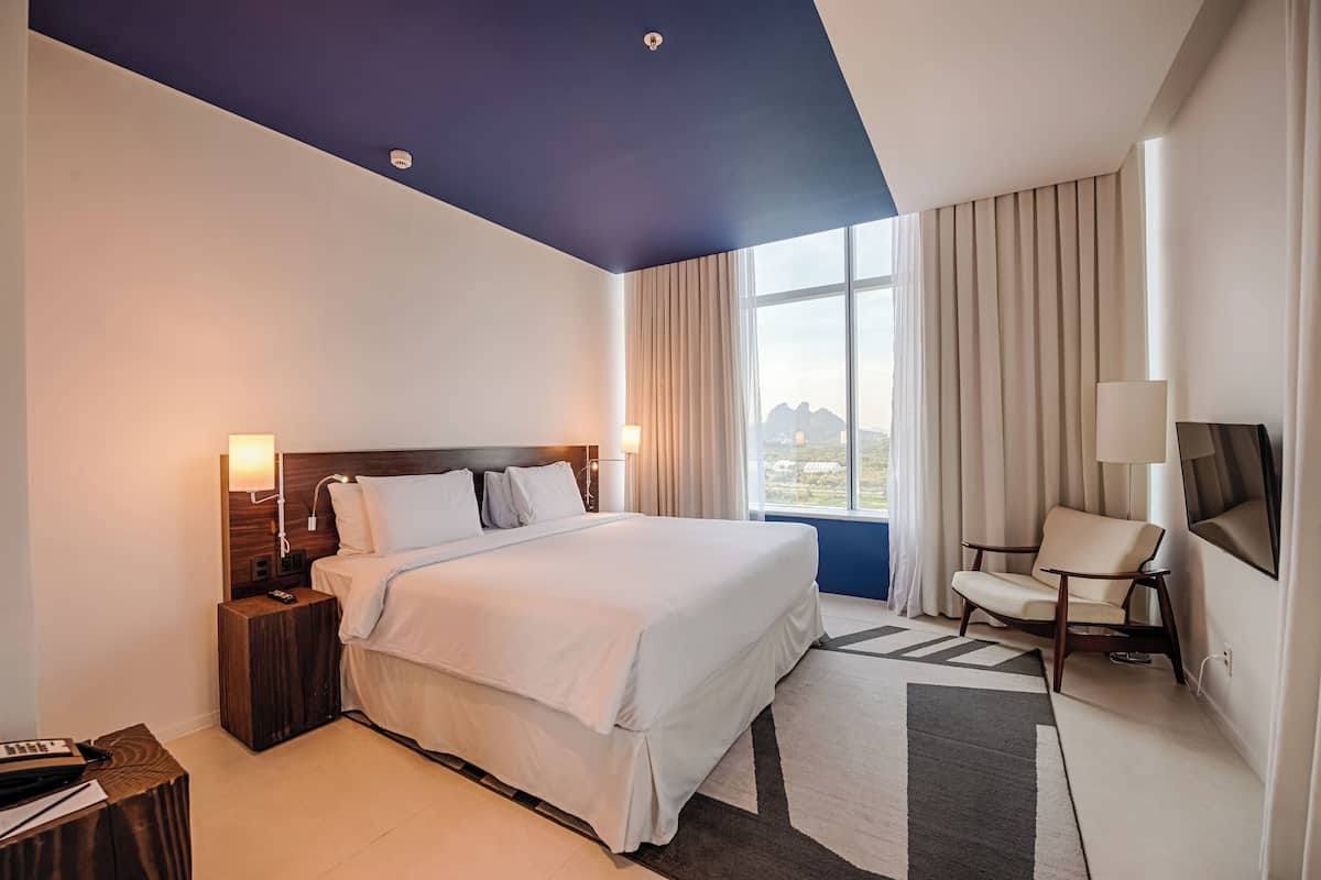 Een moderne hotelkamer met een groot bed, een bureau, een stoel en een televisie.