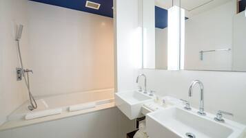 A modern bathroom with a bathtub, two sinks, and a large mirror.