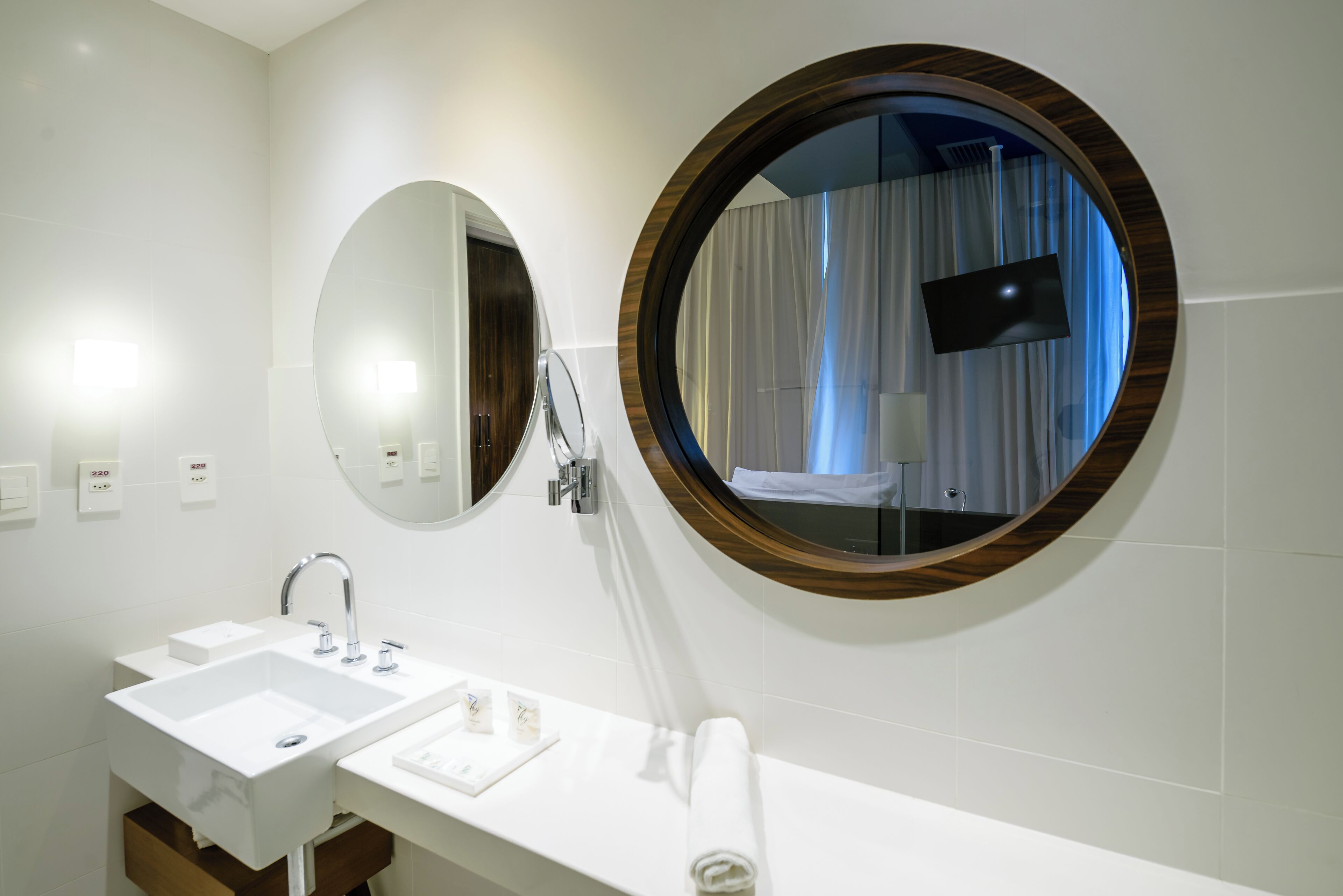 Un baño moderno con dos lavamanos, un espejo y un televisor montado en la pared.