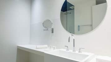 A modern bathroom with a white sink, a round mirror, and a blue accent wall.