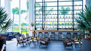 Zona de bar moderna con un ventanal grande, varios arreglos de asientos y una selección de botellas en estantes.