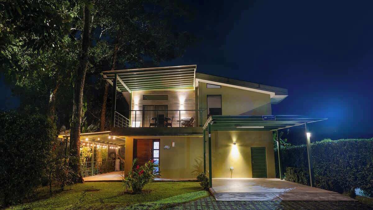 Een moderne, twee verdiepingen tellende woning met een balkon, een overdekte patio en een goed verlichte entree.