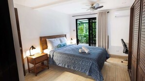 A bedroom with a bed, nightstand, desk, chair, and a view of greenery through a sliding door. - Casa del Bosque, La Fortuna, Costa Rica (La Fortuna, San Carlos)