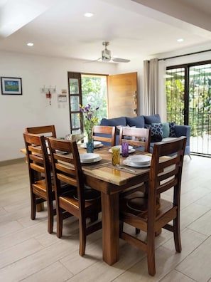 A dining area with a wooden table and chairs, a ceiling fan, and a view of the outdoors through a glass door.