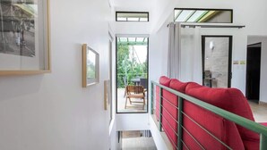 A modern interior with a red sofa, a wooden bench, and a glass door leading to an outdoor area. - Casa del Bosque, La Fortuna, Costa Rica (La Fortuna, San Carlos)