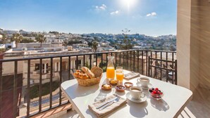 A balcony with breakfast setup, including bread, fruit, and beverages.