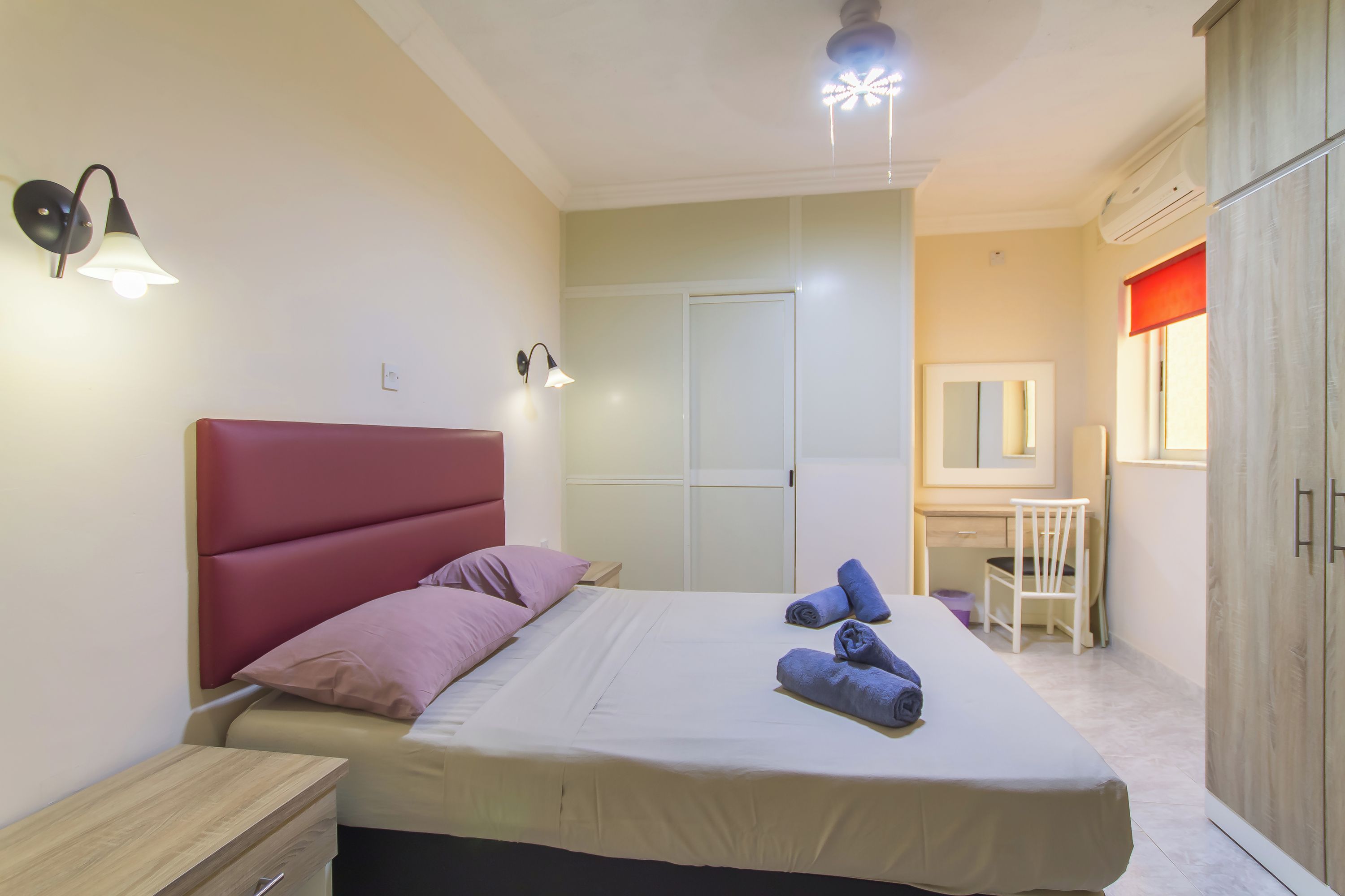 A bedroom with a bed, bedside tables, a desk, a chair, and a wardrobe.