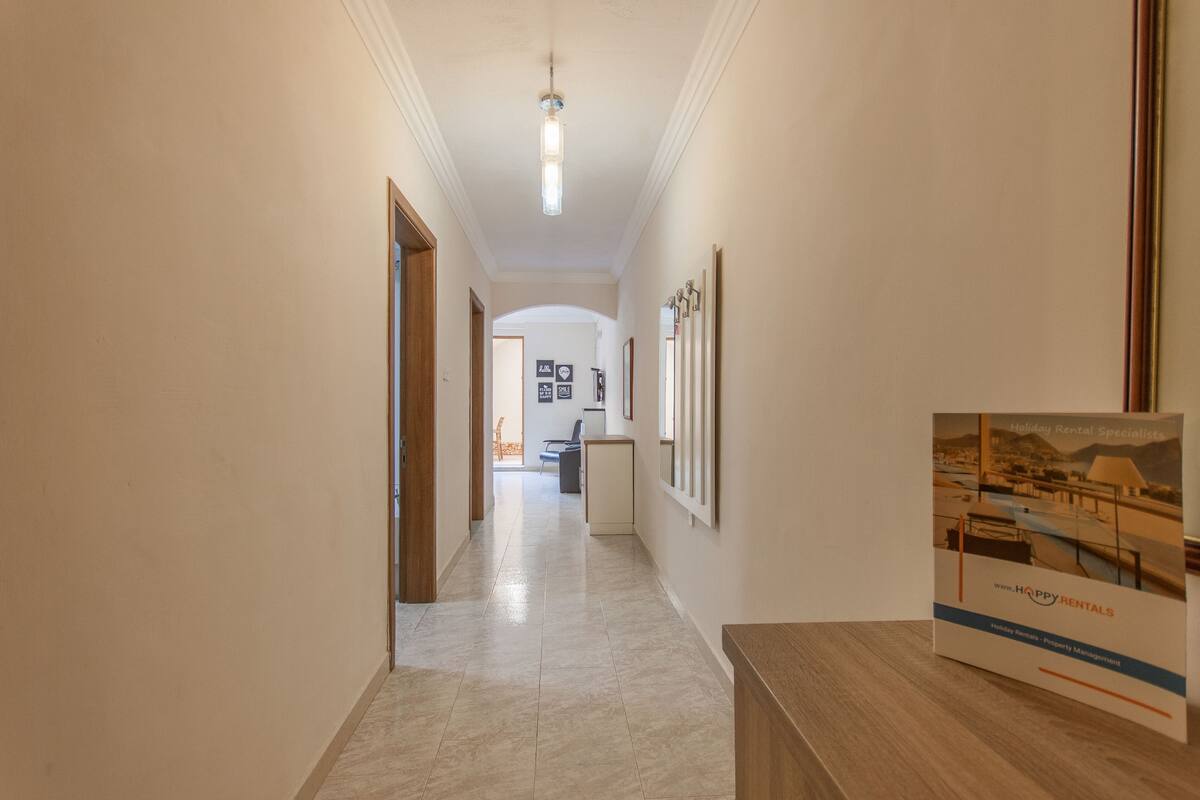 Un pasillo con un mostrador de recepción de madera, cuadros en la pared y un cartel sobre el mostrador.