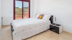 A bedroom with a bed, a nightstand, a radiator, and a balcony door.