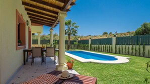 A patio with a pool, outdoor seating, and a view of the pool area.