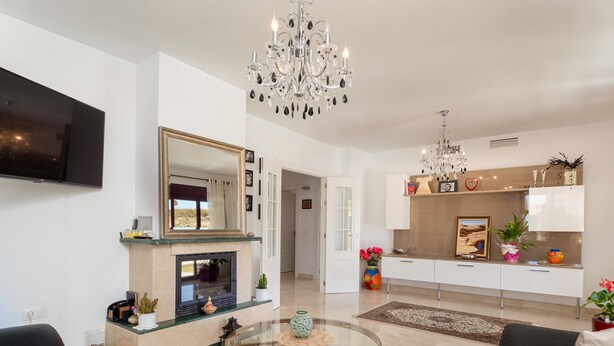 A modern living room with a fireplace, a round glass coffee table, and a sofa.