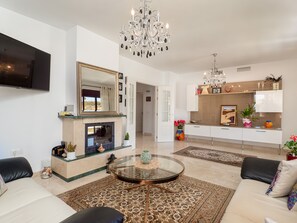 Uma sala de estar moderna com lareira, uma mesa de centro redonda de vidro e um sofá.