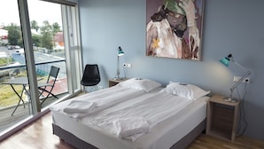 Een moderne hotelkamer met een groot bed, twee nachtkastjes, een stoel en een schilderij aan de muur.
