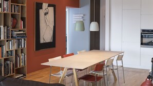 Een moderne keuken met een eethoek, met een houten tafel, stoelen en een boekenkast vol boeken.