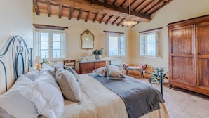 A bedroom with a large bed, wooden ceiling beams, a dresser, a mirror, and a wardrobe. - Tuscan Fizz, a traditional Stone Farmhouse with Private Pool and Amazing View among the Vineyards in Lucca (Lucca)