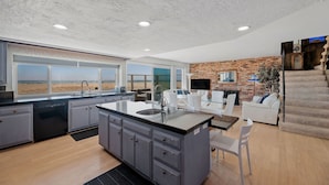 Una cocina moderna con una isla grande, un comedor con un sofá blanco y una pared de ladrillo.