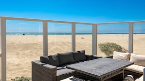 Una habitación iluminada por el sol con vistas a la playa, que incluye un sofá de mimbre y una mesita.