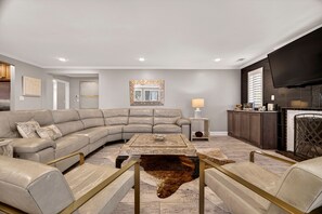 Ein modernes Wohnzimmer mit einer Eckcouch, einem Couchtisch, einem Kamin und einem an der Wand befestigten Fernseher.