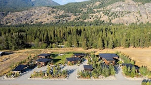 Un quartier résidentiel composé de plusieurs maisons, entouré de forêts denses et avec des montagnes en arrière-plan.