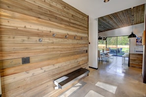 Un intérieur moderne avec des murs lambrés en bois, un banc intégré et une vue sur un patio extérieur.