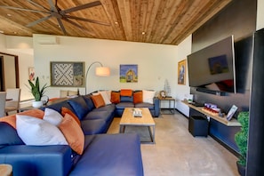 A modern living room with a sectional sofa, a coffee table, a TV, and artwork on the walls. - Base Camp 49 - Flagg Mountain Cabin 7B (Mazama)