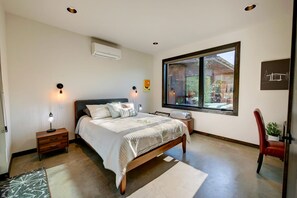 Un dormitorio con cama, lámparas de noche, una ventana y vistas al exterior.