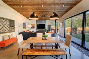 A modern kitchen with a dining area, wooden ceiling, and large windows. - Base Camp 49 - Goat Peak Cabin 11A (Mazama)