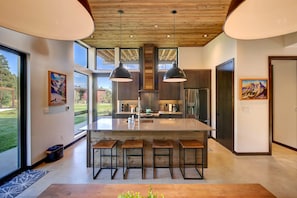 A modern kitchen with a central island, pendant lighting, and a view of the outdoors. - Base Camp 49 - Goat Peak Cabin 11A (Mazama)