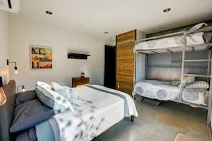 A modern bedroom with a bunk bed, a single bed, and a bedside table with a lamp. - Base Camp 49 - Lucky Jim Cabin 11B (Mazama)