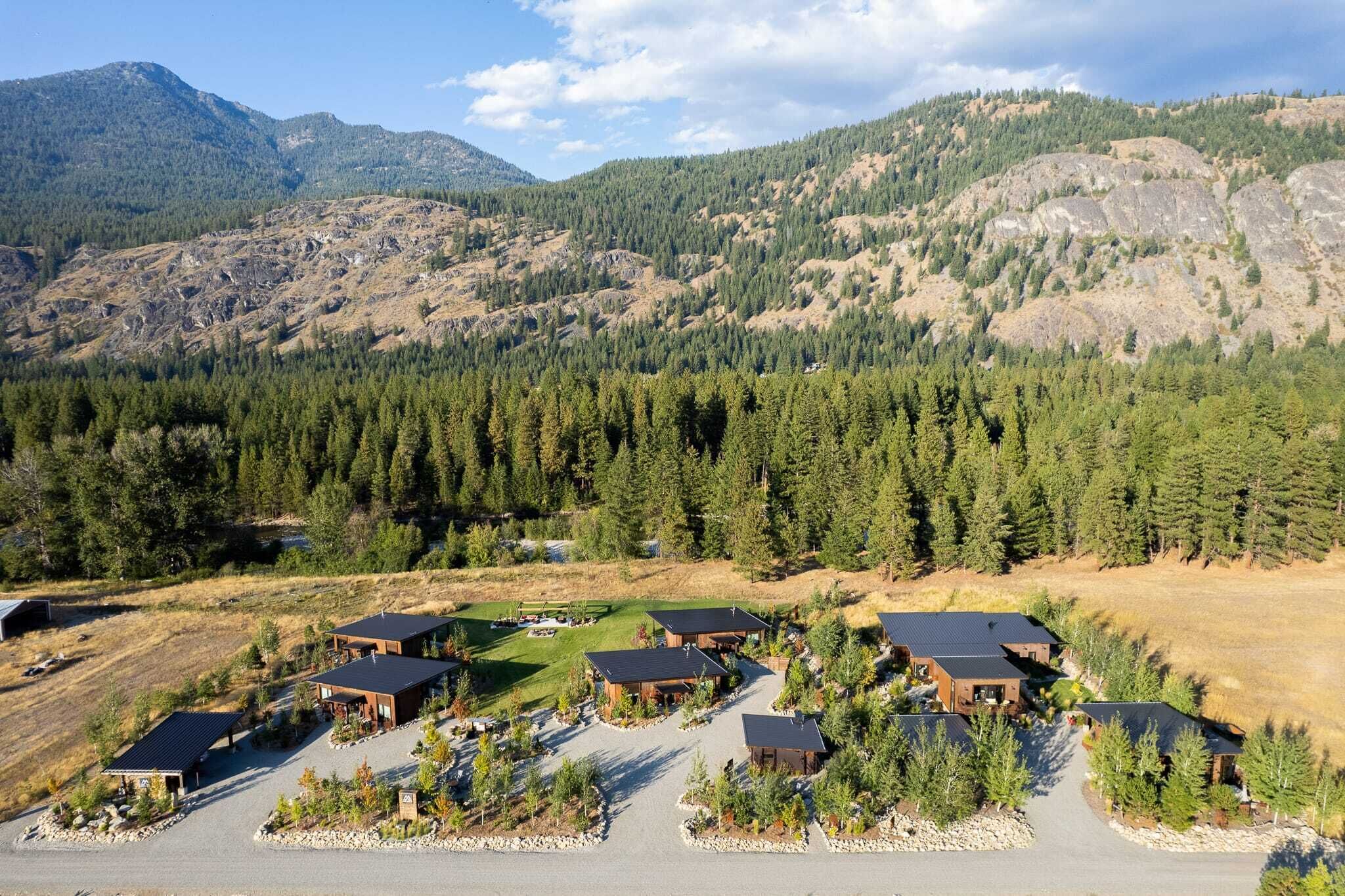 Un quartier résidentiel composé de plusieurs maisons, entouré de forêts denses et avec des montagnes en arrière-plan.