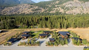 A residential area with multiple houses surrounded by dense forests and mountains in the background. - Base Camp 49 - Lucky Jim Cabin 11B (Mazama)