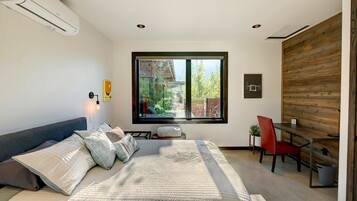 Un dormitorio moderno con una cama grande, un escritorio y un ventanal.