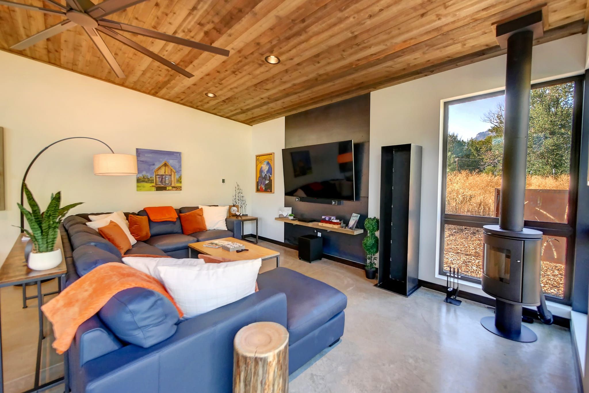 Una sala de estar moderna con un sofá modular, un televisor de pantalla plana, una chimenea y un ventanal con vistas al exterior.