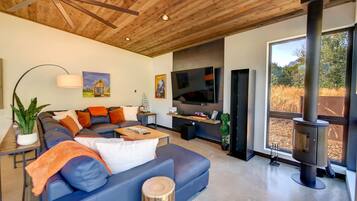 Una sala de estar moderna con un sofá modular, un televisor de pantalla plana, una chimenea y un ventanal con vistas al exterior.