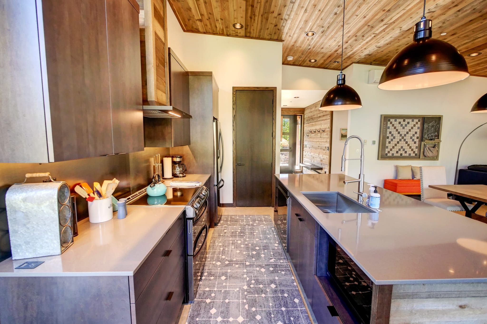 Una cocina moderna con una isla central, electrodomésticos de acero inoxidable e iluminación colgante.