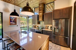 A modern kitchen with a large island, stainless steel appliances, and wooden cabinetry. - Base Camp 49 - Sandy Butte Cabin 7A (Mazama)