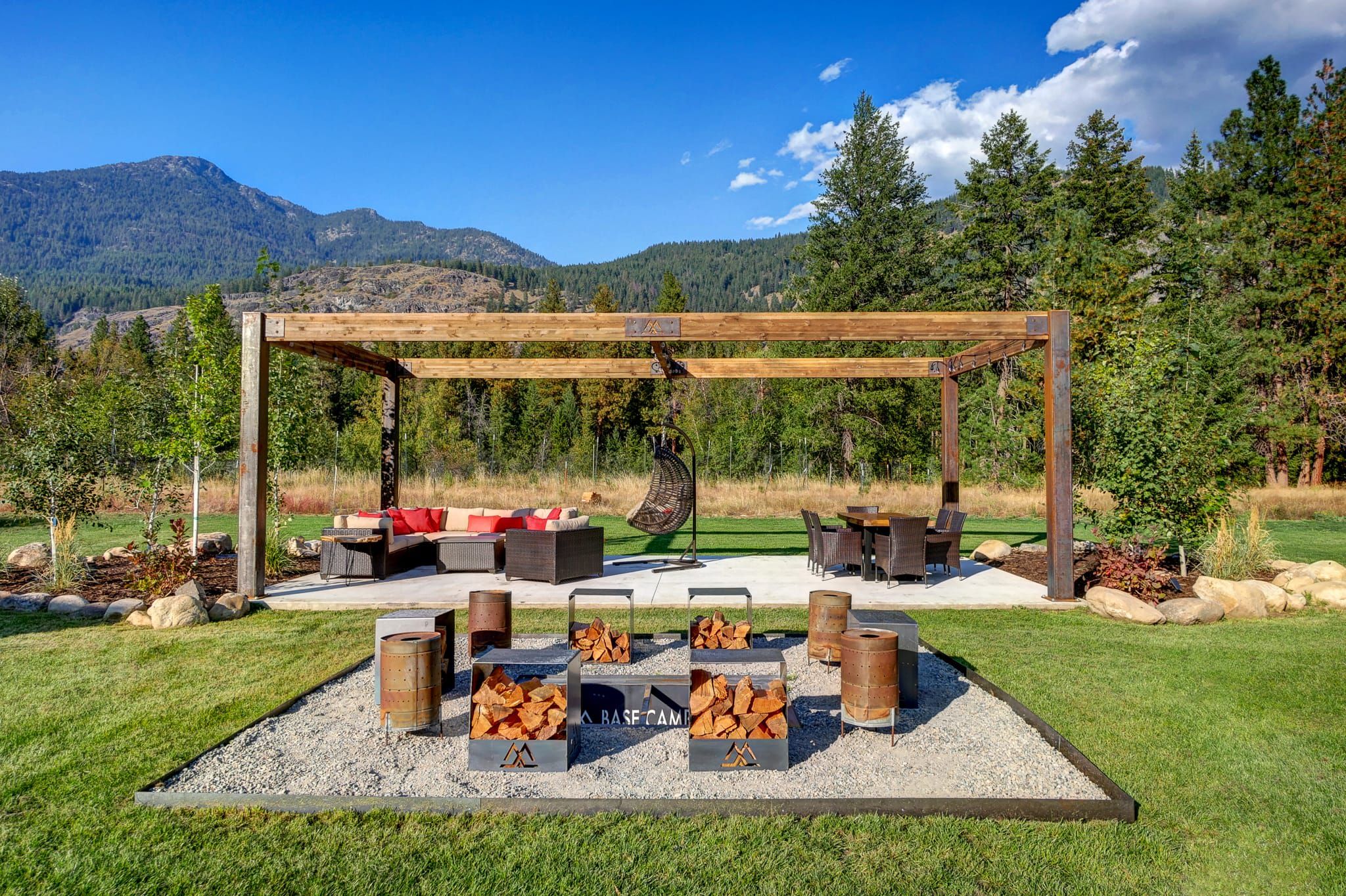 Un patio exterior con una pérgola, mobiliario y leña.