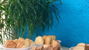 A buffet table with labeled dishes including pão suico, rabanada, and sanduíche. - Pousada Turquesa by Gente Bonita (Búzios)