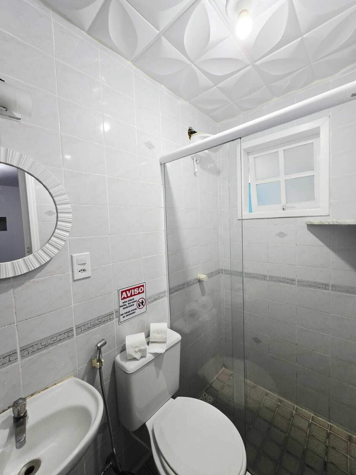 Une salle de bain comprenant des toilettes, un bidet, un lavabo et une douche avec une porte en verre.