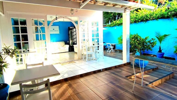 A patio area with a table and chairs, a blue wall, and potted plants. - Pousada Turquesa by Gente Bonita (Búzios)